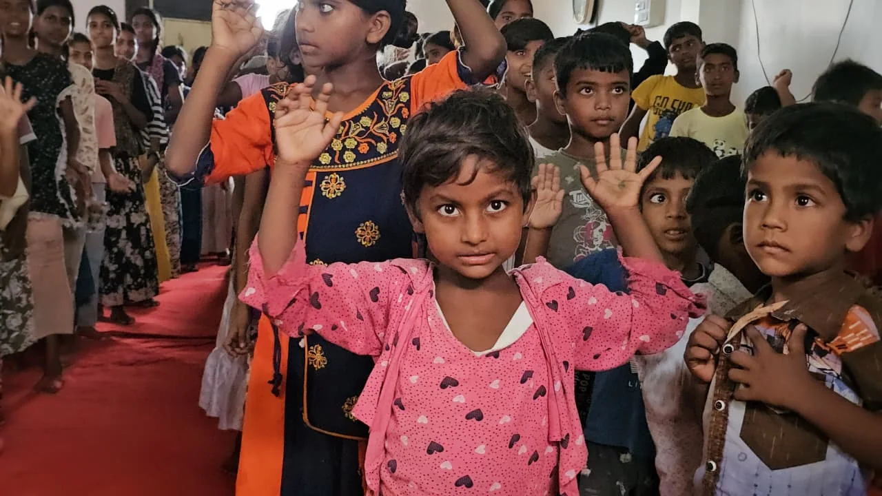 Children singing with their hands raised