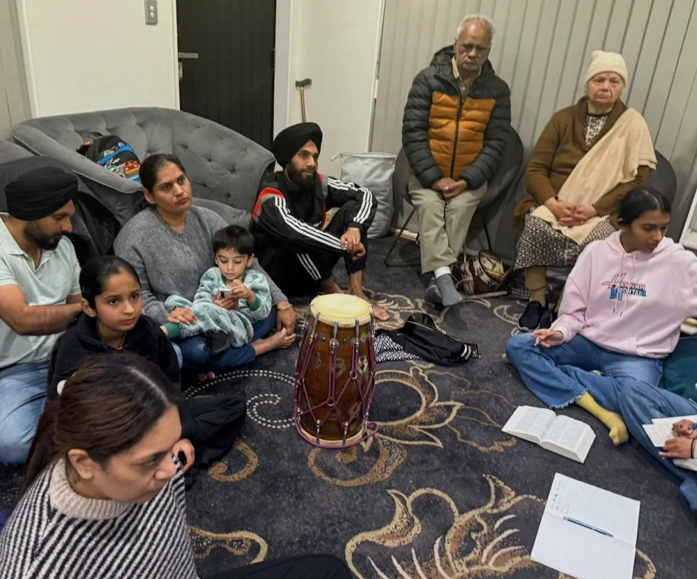 Families sitting together with instruments at a home gathering