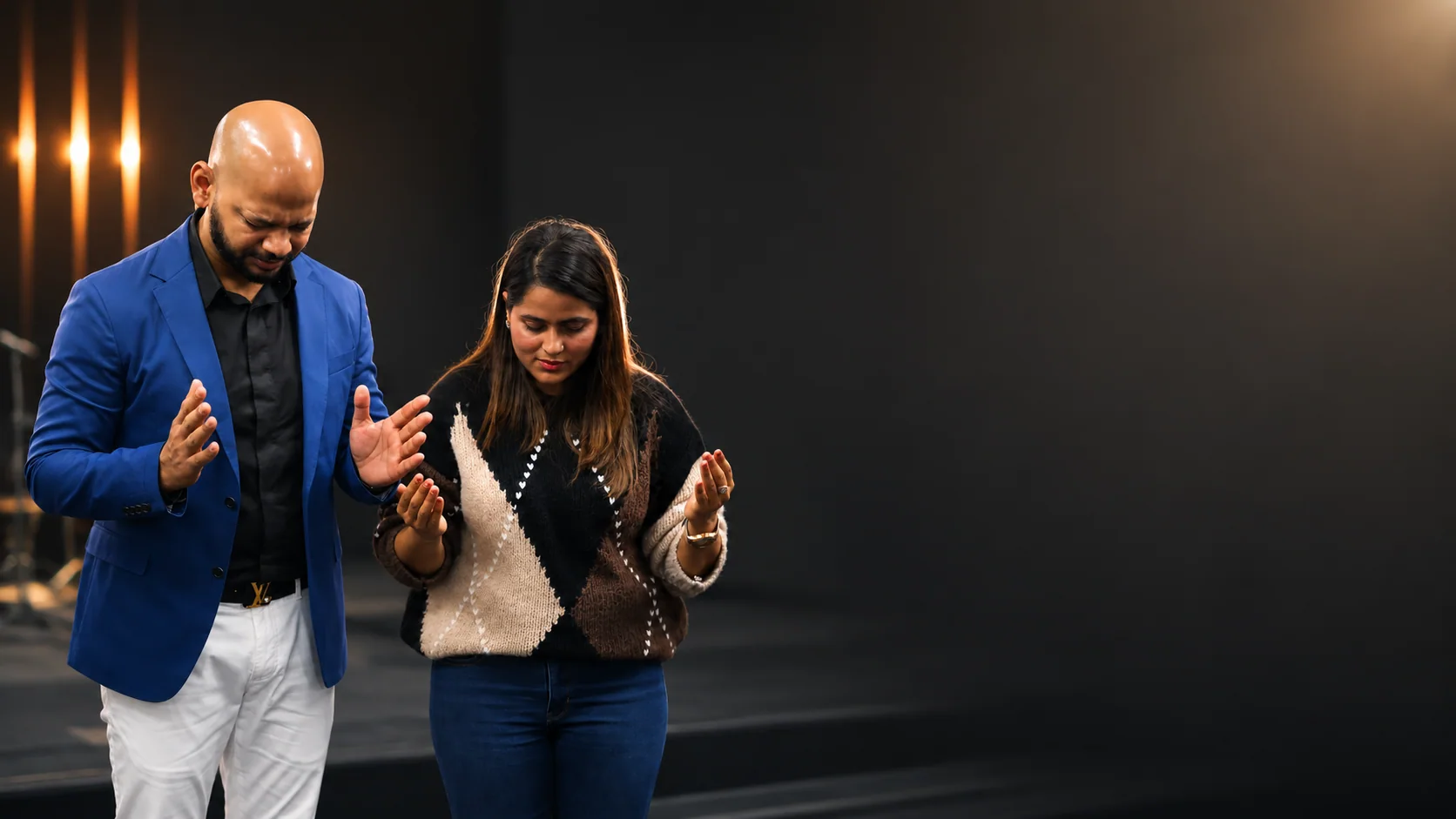 Two people standing in prayer with open hands