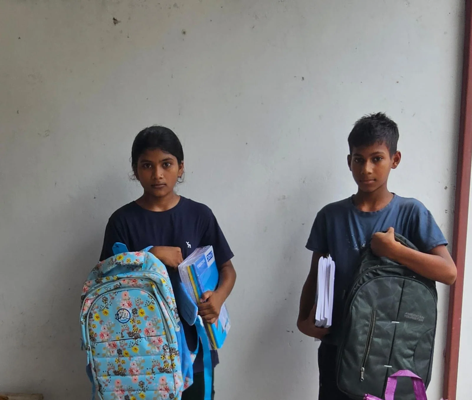 Two boys with the school backpacks and books they have been given