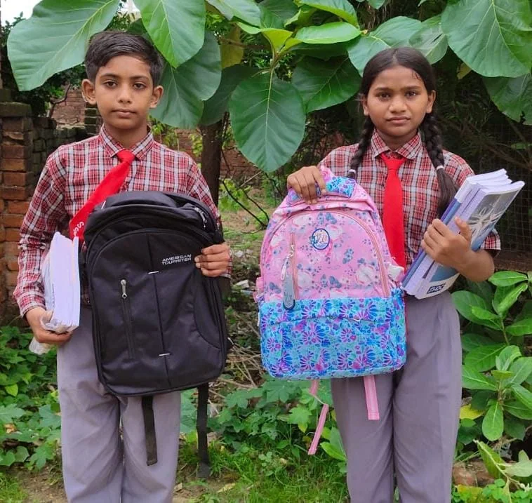 Two children in school uniform with their new backpacks and books